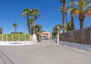 una recinzione su una strada con palme e una casa di Mobil-home de Laura et Angélique au camping ''Le Neptune'' jusqu'à 4 personnes ad Argelès-sur-Mer