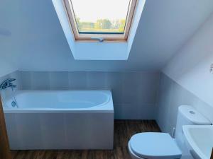 a bathroom with a toilet and a bath tub and a window at Dom Wakacyjny Bogaczewo in Bogaczewo +23 photos