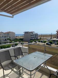 a glass table and chairs on a balcony with a view at KLIO Apartments and Studios in Nei Poroi