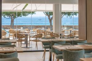 a restaurant with tables and chairs and a view of the ocean at Hotel Palia Tropico Playa in Palmanova
