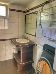 W łazience znajduje się umywalka, lustro i krzesło. w obiekcie Jázmin Apartmanok w mieście Mórahalom