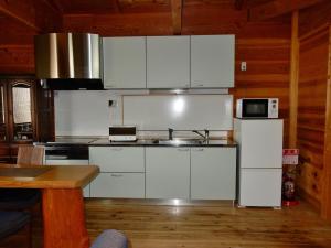 Una cocina con gabinetes blancos, un fregadero y un microondas. en Yadoya Sanbou, en Kioto