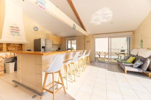a kitchen and living room with a counter and chairs at La Maison Paradis - Piscine privée et chauffée in Luçon