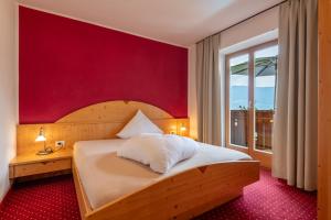 a bedroom with a bed with a red wall at Hotel Residence MaVie in Lagundo +100 photos