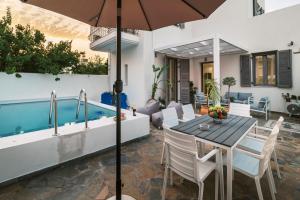 a patio with a table and chairs and a swimming pool at Koskinou Escape Villa in Koskinou