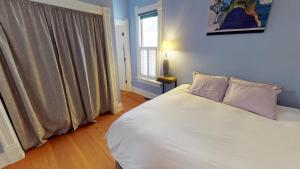 a bedroom with a white bed and a window at Just Two Blocks From Downtown Bozeman, The Dahlia House Is A Tucked Away Retreat in Bozeman