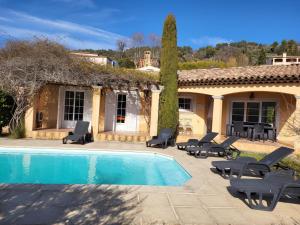 a villa with a swimming pool with chairs and a house at Callian - Très belles Villas, 3 chambres et piscine privée in Callian