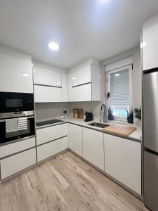 een keuken met witte kasten en roestvrijstalen apparaten bij CASA NIEVES Centro Moaña in Moaña