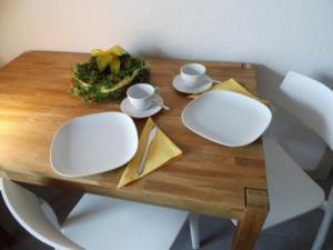 - une table en bois avec des assiettes et des tasses blanches dans l'établissement Gästezimmer Haus Tulpenstraße, à Elsfleth