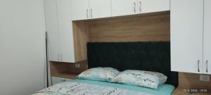 a bed with a green headboard and two pillows at CENTAR CEPERKOVIC in Vrnjačka Banja