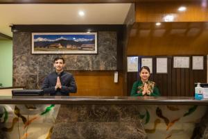 un homme et une femme debout à un comptoir avec leurs mains en prière dans l'établissement Mount Kailash Resort, à Pokhara