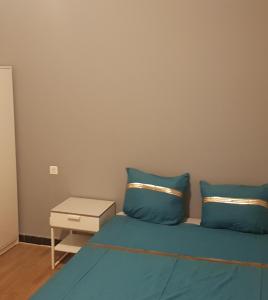 Una cama con almohadas azules y una mesa auxiliar. en Apprt'Nadia, en Aviñón