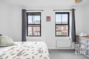 a bedroom with a bed and two windows at OnSiteStays Dartford 4BR House with Garden, bathroom and ensuite in Dartford