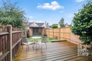 a patio with a table and chairs on a wooden deck at OnSiteStays Dartford 4BR House with Garden, bathroom and ensuite in Dartford