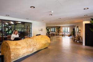een vrouw aan een bureau in een lobby met een groot houtblok bij Veluwe Hotel De Beyaerd in Hulshorst +37 foto's