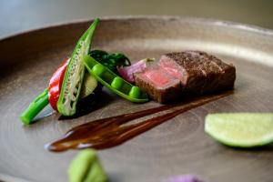 a plate of food with a piece of meat and vegetables at Glamday Style Okinawa Yomitan Hotel & Resort in Yomitan