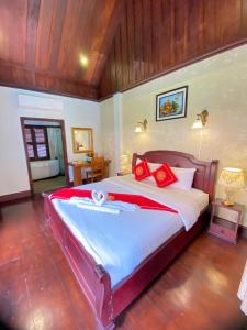 a bedroom with a large bed with red pillows at Luangprabang Villa Kee Lee in Luang Prabang