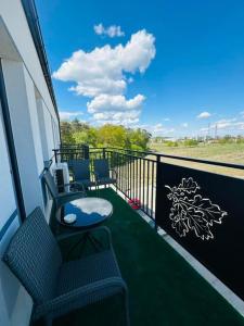 a balcony with two chairs and a view of a field at Apartamenty Dębowa 27 in Milicz