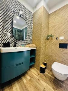 a bathroom with a blue sink and a mirror at Apartamenty Dębowa 27 in Milicz +7 photos