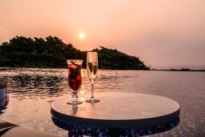 two glasses of wine sitting on a table in the water at Glamday Style Okinawa Yomitan Hotel & Resort in Yomitan