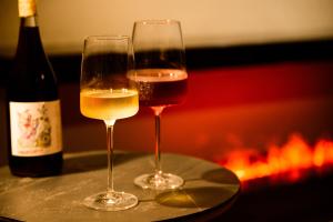 two glasses of wine sitting on a table next to a fireplace at Glamday Style Okinawa Yomitan Hotel & Resort in Yomitan