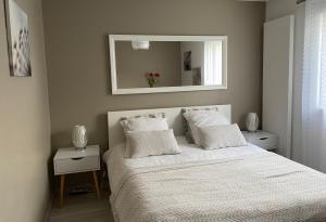 a bedroom with a white bed with a mirror at Appartement neuf au calme proche du lac in Saint-Jorioz