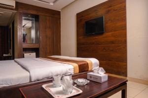 a bedroom with a bed and a table and a tv at Hotel Mayfair in Lahore +43 photos