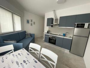 ガビッチェ・マーレにあるResidenze Porto Canaleのキッチン、リビングルーム(テーブル、青いソファ付)