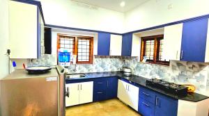 a kitchen with blue cabinets and a stainless steel refrigerator at Dean Dale Cottages in Thekkady