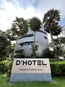 新加坡D'Hotel Singapore managed by The Ascott Limited的棕榈树建筑前的标志
