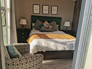 イースト・ロンドンにあるClassy Beach Apartmentのベッドルーム1室(緑のヘッドボード付きのベッド1台、椅子付)