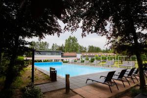een zwembad met ligstoelen naast een gebouw bij Veluwe Hotel De Beyaerd in Hulshorst