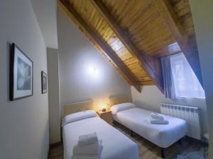 2 letti in una camera con soffitto in legno di Eth Palai a Vielha