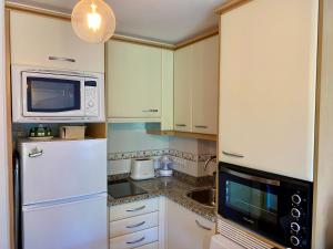 a kitchen with a white refrigerator and a microwave at Apto 2D en primera línea de Playa Langosteira con garaje y wifi in Finisterre +31 photos