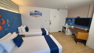a hotel room with two beds and a desk and a television at Days Inn by Wyndham Patong Beach in Patong Beach