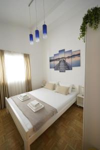 a white bedroom with a large bed in a room at Apartments Loncar-near Zrće beach in Novalja