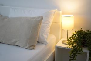 a bed with a pillow and a lamp and a plant at Apartments Loncar-near Zrće beach in Novalja