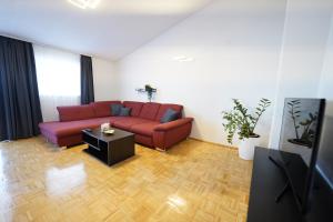 a living room with a red couch and a table at Apartments Loncar-near Zrće beach in Novalja