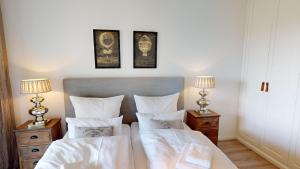 a bedroom with two beds with white sheets and two lamps at Südkap B-03 in Pelzerhaken