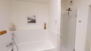 a white bathroom with a shower and a sink at Südkap B-03 in Pelzerhaken +35 photos