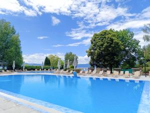 a large swimming pool with chairs and umbrellas at Hotel Metropol – Metropol Lake Resort in Ohrid