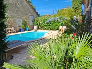 a swimming pool in a garden with flowers and plants at Le gîte de Sainte Valière PISCINE,SPA et CLIMATISATION in Sainte-Vallière