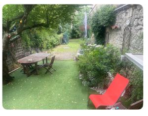 a garden with a table and a red chair at Chambre privée Yoko in Talence