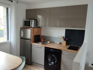 a kitchen with a washer and a sink and a refrigerator at Studio au calme avec jardin in Trémuson