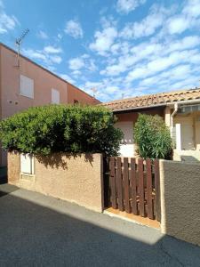 a fence in front of a building with bushes at Maison à 150 m Plage 6LT221 in Saint Pierre La Mer +9 photos