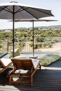 a patio with a table and an umbrella on a deck at Casa Kalu in São Brás de Alportel