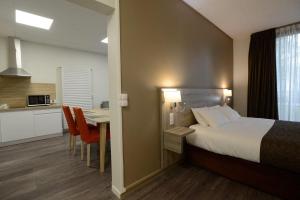 a bedroom with a bed and a table and a kitchen at Brit Hotel du Lac in Saint-Paul-lès-Dax