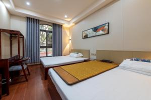 a room with two beds and a desk and a window at Kaibu Courtyard Superior Apartment, Changjiang Cable Car Nanbin Road, Chongqing in Chongqing