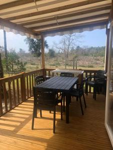 a wooden deck with tables and chairs on it at Les dunes de Contis Chez Edith océan pins et détente assurée dans camping 4 étoiles in Saint-Julien-en-Born