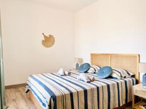 a bed with blue and white striped sheets and pillows at Front de mer Beau T3 climatisé Balcon Parking Ajaccio in Ajaccio